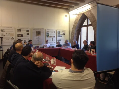 La comunitat reunida a la primera trobada, al voltant d’una taula en una sala amb arcades